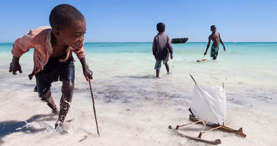 Enfants malgaches en train de jouer avec un bateau en bois dans l'Océan Indien
