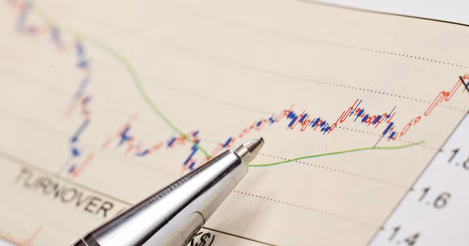 Graphique financier avec un crayon posé dessus représentant la bourse et les investissements 