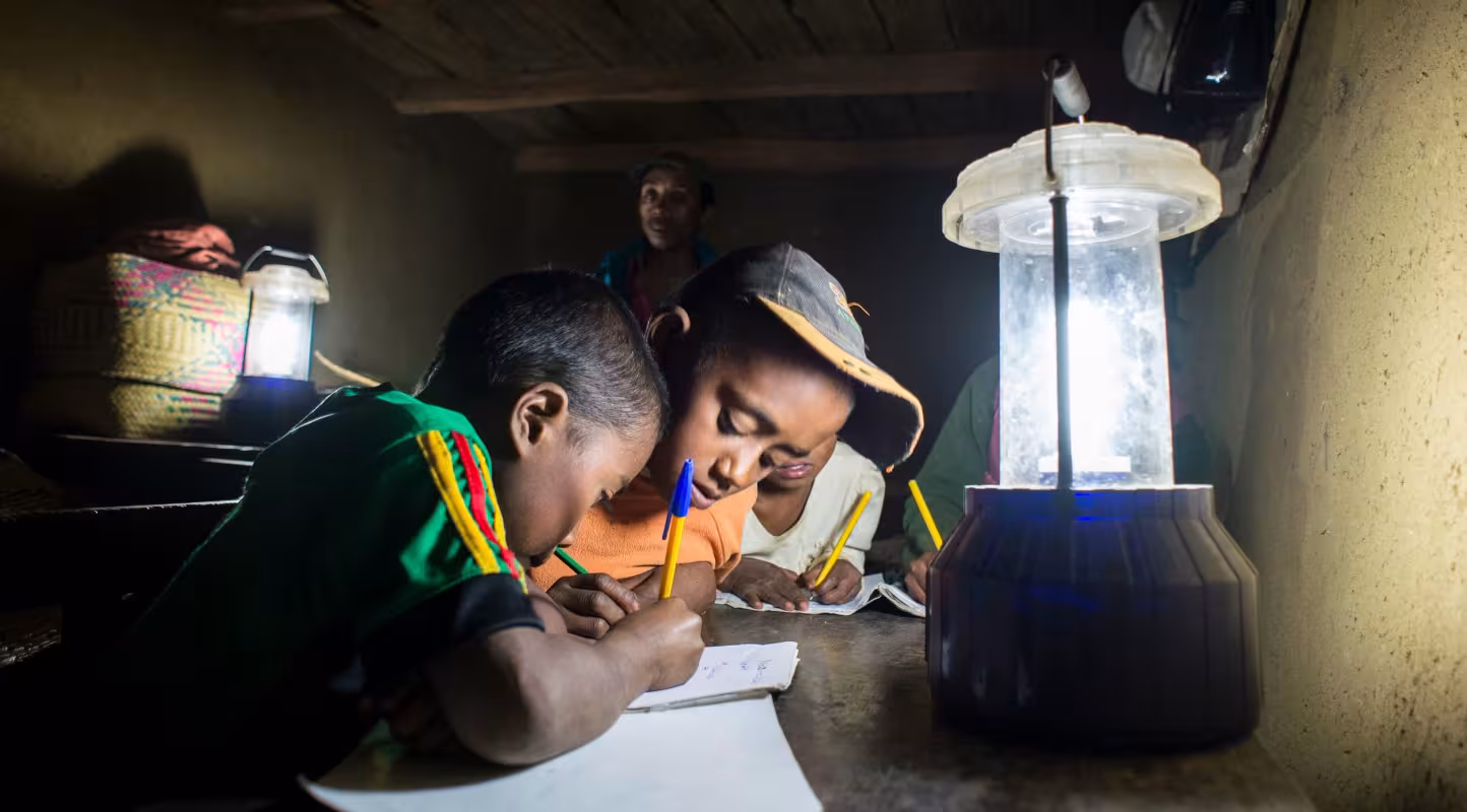 Enfant qui étudie à la lueur d'une lampe solaire à Madagascar
