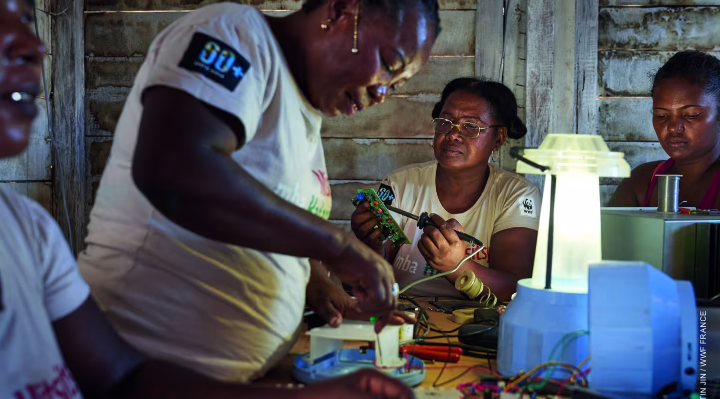 Les grands-mères "solaires" travaillent à l'installation de batteries, de régulateurs et lampes LED pour illuminer leur village d'Ambakivao (Madagascar)