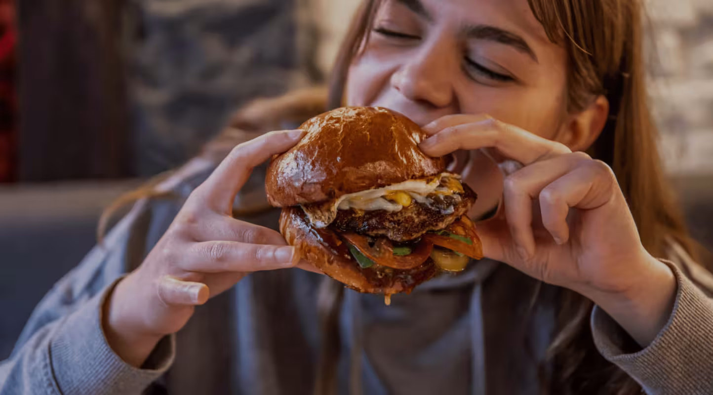 Jeune fille mangeant un hamburger appétissant, défi au mythe des protéines animales
