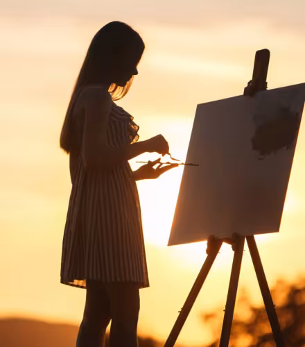 Femme qui peint devant un coucher de soleil