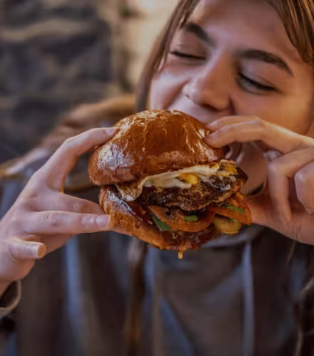 Jeune fille mangeant un hamburger appétissant, défi au mythe des protéines animales
